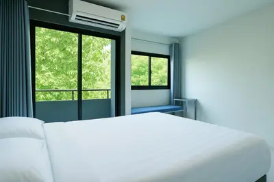 a white bed in a room with two windows at Siam Rama9 Hotel in Amphoe Phra Khanong