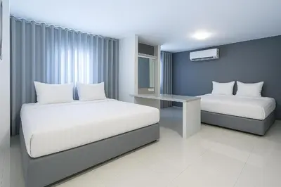 a hotel room with two beds and a desk at Siam Rama9 Hotel in Amphoe Phra Khanong