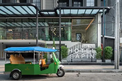 a green golf cart parked in front of a building at Hotel Sapin in Pom Prap