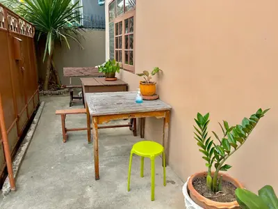 a table and a yellow stool in a room with plants at DonMueang Boutique House DonMueang Airport in Bangkok
