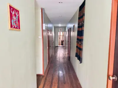 a hallway with a long corridor with wooden floors and walls at DonMueang Boutique House DonMueang Airport in Bangkok