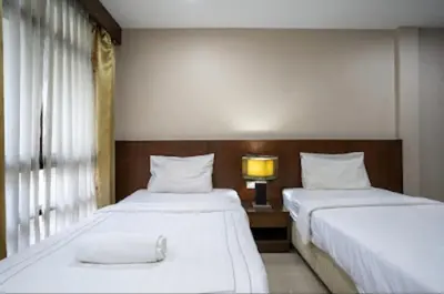 a bedroom with two beds and a lamp and a window at IRAQI HOTEL in Makkasan