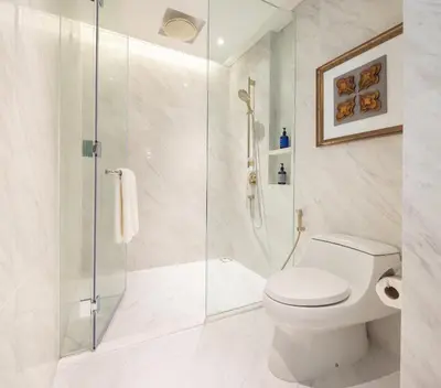 a bathroom with a toilet and a glass shower at Eastin Grand Hotel Phayathai in Bangkok