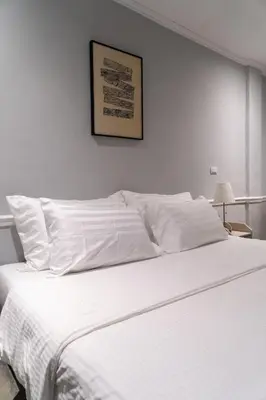 a white bed with white sheets and a picture on the wall at Baansuansao in Bang Rak