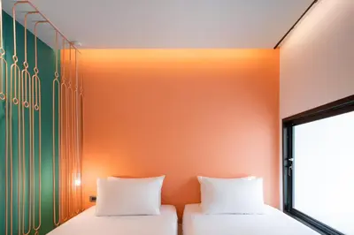 two beds in a room with an orange and green wall at Speck Bangkok in Bangkok