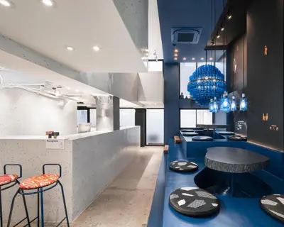 a restaurant with blue counters with stools and a table at Speck Bangkok in Bangkok