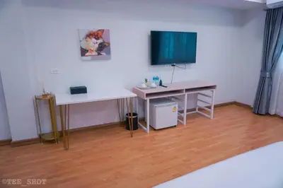a room with a desk and a television on a wall at Siam Best Inn in Makkasan