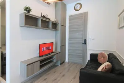 a living room with a black couch and a television at New Condo, Hi-Speed Wi-Fi, Gym Pool, near Lam Sali MRT in Bangkok