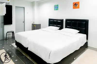 a bedroom with a large white bed with black headboard at Suksomboon Residence in Bangkok
