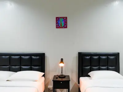 a bedroom with two beds and a clock on the wall at Suksomboon Residence in Bangkok