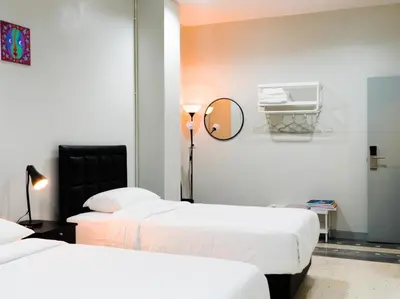 a hotel room with two beds and a mirror at Suksomboon Residence in Bangkok