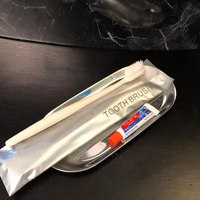 a toothbrush and a toothpaste packet on a table at Suksomboon Residence in Bangkok