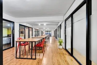 a long dining room with a table and red chairs at Chill Inn Bangkok in Bang Kapi