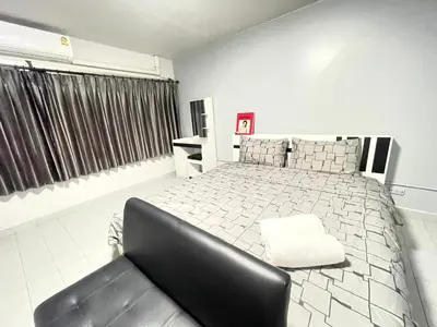 a bedroom with a large bed and a black chair at Impact Arena C3 Milo in Nonthaburi