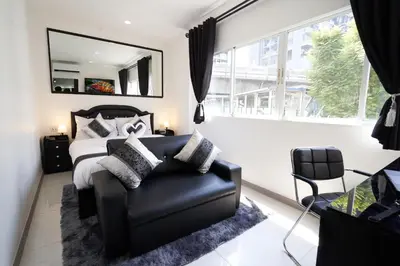 a bedroom with a bed and a chair and a mirror at Thonglor Suites Hotel in Bangkok