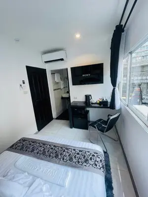a room with a bed and a desk and a television at Thonglor Suites Hotel in Bangkok