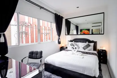 a bedroom with a bed with a mirror and a chair at Thonglor Suites Hotel in Bangkok