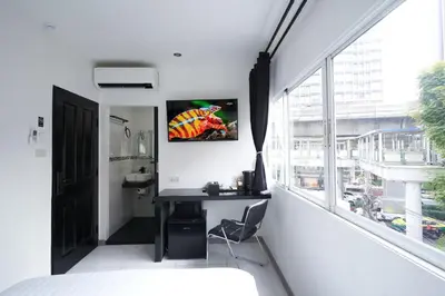 a desk in a room with a large window at Thonglor Suites Hotel in Bangkok