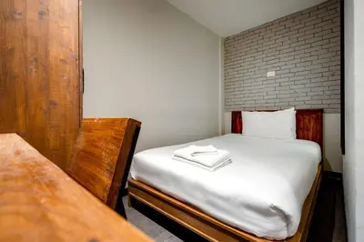 a small bedroom with a bed with white sheets at XX GO INN Sukhumvit 20 Bts Asoke-Phrom Phong in Bangkok