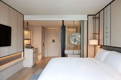 a bedroom with a large white bed and a bathroom at dusitD2 Samyan Bangkok in Bangkok