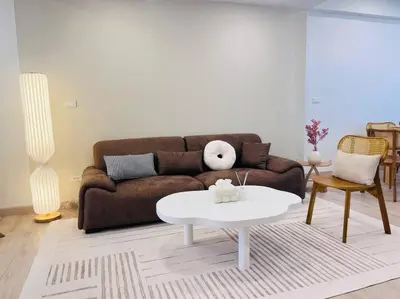a living room with a brown couch and a white table at BKK Villa/Huaikwang China Twon in Bangkok