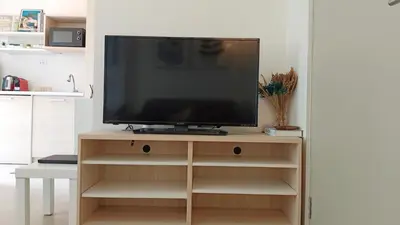 a television on a wooden stand in a living room at Elio Del Ray in Bangkok