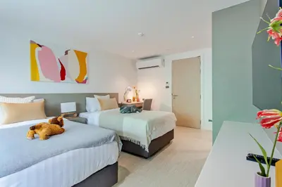 a bedroom with two beds and a teddy bear laying on the bed at GM Residence in Bangkok