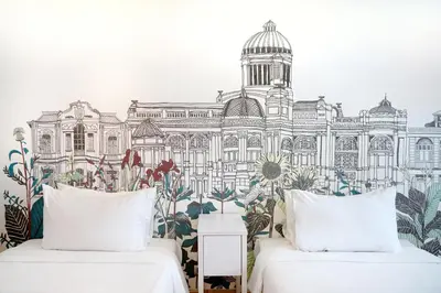 two beds in front of a mural of a building at Beat Hotel Bangkok in Bangkok