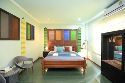 a bedroom with a bed and a chair in it at นอนในสวน รีสอร์ท in Bangkok