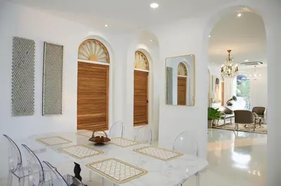 a white dining room with a table and chairs at Arpo Pool Villa Riverside Bangkok in Bangkok
