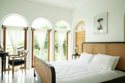 a bedroom with a bed and a desk and windows at Arpo Pool Villa Riverside Bangkok in Bangkok