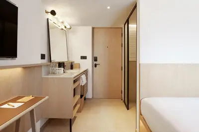a small bathroom with a bed and a sink at ASAI Bangkok Sathorn in Bangkok