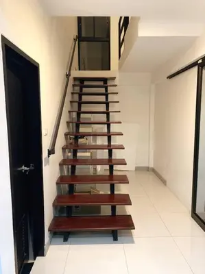 a wooden staircase in a room with a door at Joyful Modern Home with Foods and MRT Rama 9 Nearby in Bangkok