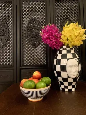 a table with a bowl of fruit and a vase with flowers at Central Bangkok, 5 stars river view & characteristic decor in Bangkok