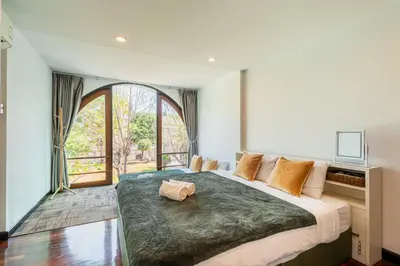 a bedroom with a large bed with a large window at Bangkok Cozy Garden Pool Villa Sukhumvit in Amphoe Phra Khanong