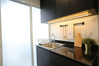 a kitchen with black cabinets and a sink and a window at WoodGreen Room near Chatuchak Weekend Market in Bangkok