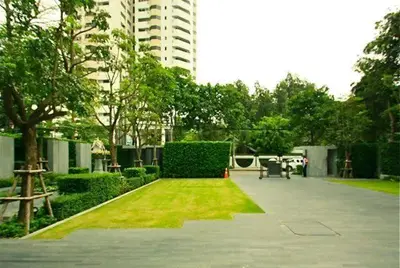 a park with green grass and a bench and buildings at Luxury 2BR on the Clouds in Prime area Bangkok in Bangkok