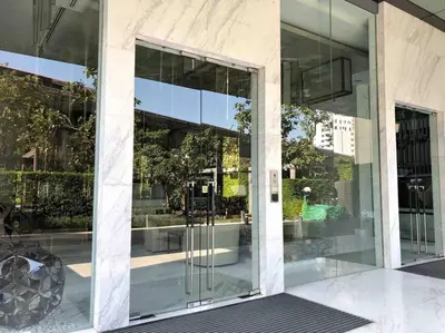 a glass facade of a building with a revolving door at 1BR Luxury Condo 50m to Thonglor BTS station in Bangkok