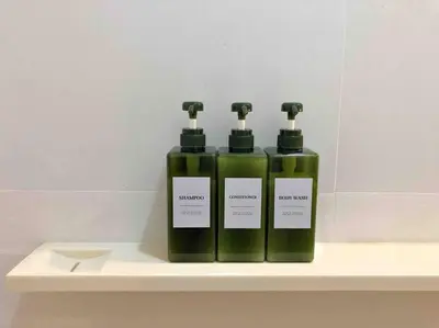 two green bottles of soap sitting on a shelf at 1BR Luxury Condo 50m to Thonglor BTS station in Bangkok