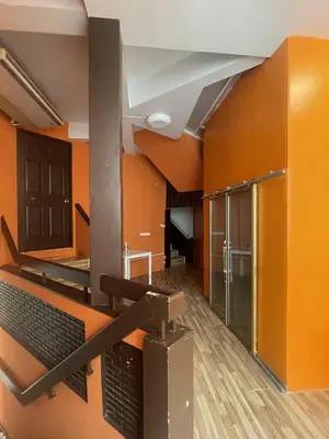 an empty room with orange walls and a staircase at Doodle Lodge Bangkok in Bangkok