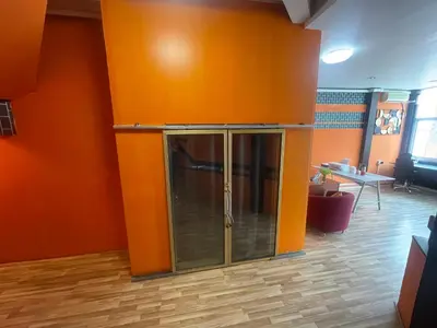 an orange wall with a glass door in a room at Doodle Lodge Bangkok in Bangkok