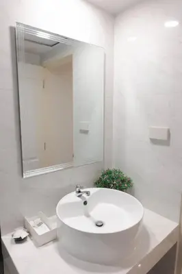 a white bathroom with a sink and a mirror at BnB98 Silom Hotel in Bangkok
