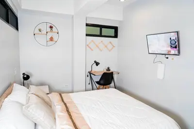 a bedroom with a bed and a tv and a desk at BnB98 Silom Hotel in Bangkok