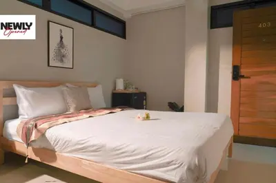 a bedroom with a large white bed with a wooden door at BnB98 Silom Hotel in Bangkok