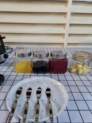 a table with a plate and two spoons and jars of jam at Met A Space Pod @Phrom Phong in Bangkok