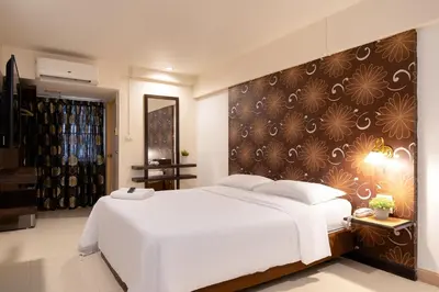 a bedroom with a large white bed and a wall at Synsiri Lat Phrao 83 in Ban Zong Katiam