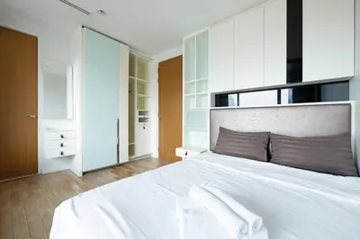 a bedroom with a large white bed with white cabinets at M Estate 2BR Private Residence, 300m to BTS Chit Lom in Bangkok