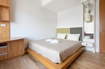 a bedroom with a bed with white sheets and a window at M Estate 2BR Private Residence, 300m to BTS Chit Lom in Bangkok