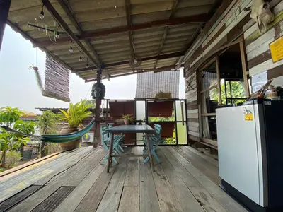 a patio with a table and a refrigerator on a deck at Baan GoLite Ko Kret - บ้านโกไล้เกาะเกร็ด in Nonthaburi