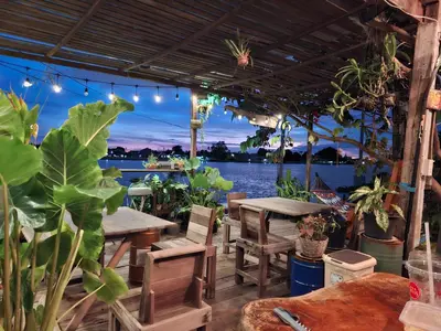 a patio with tables and chairs and a view of the water at Baan GoLite Ko Kret - บ้านโกไล้เกาะเกร็ด in Nonthaburi